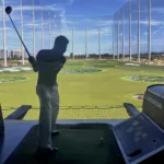 David Murillo hitting a golf ball at a Topgolf driving range