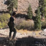 David Murillo hiking a rocky mountain trail among pine trees